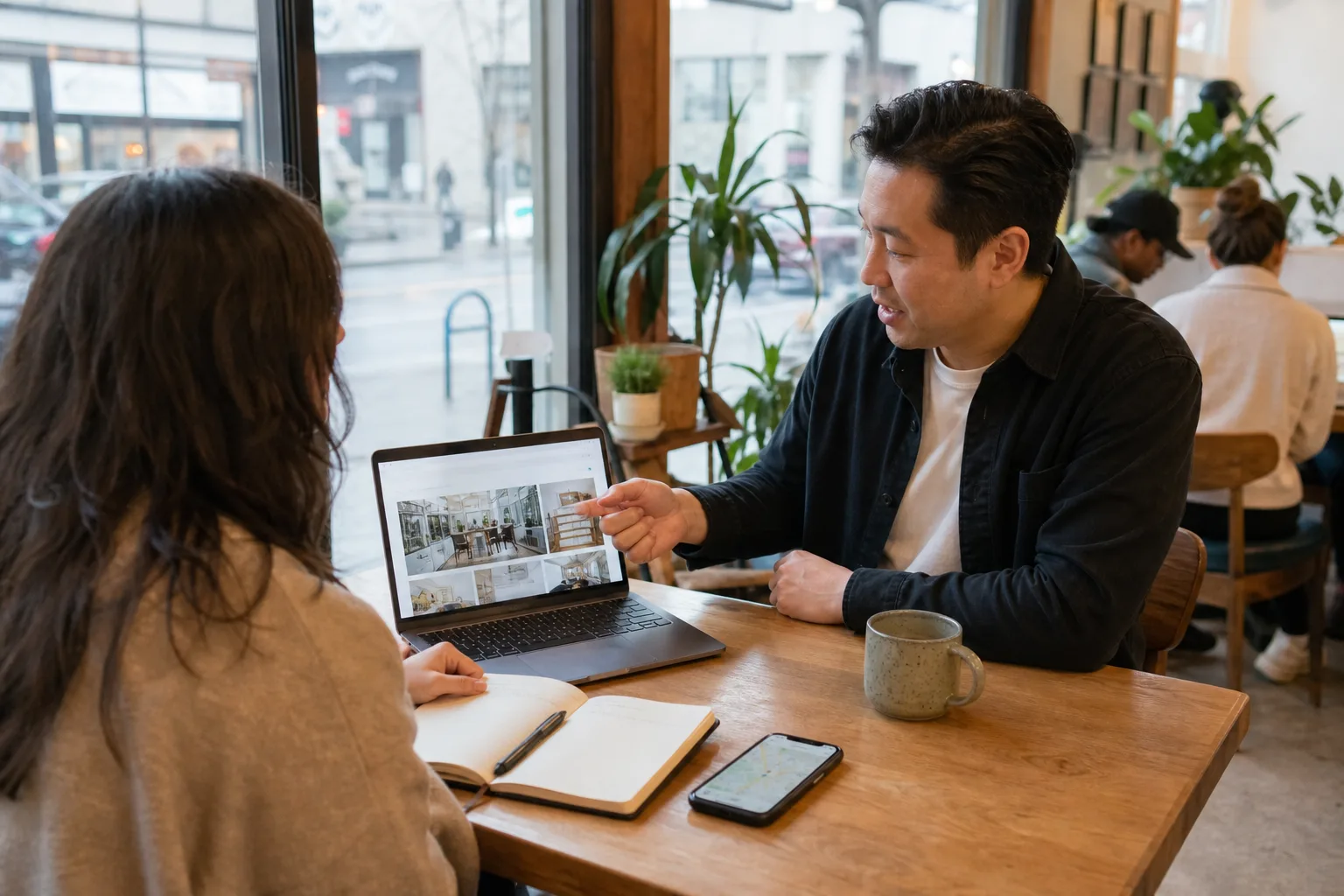 Small business owner reviewing a digital marketing agency website with a web designer in a cafe