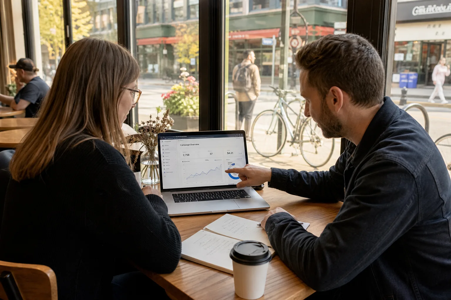 Small business owner reviewing marketing options with a consultant in a cafe near a storefront
